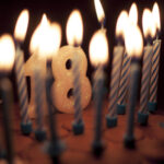 Birthday cake with lit candles including '18' candle